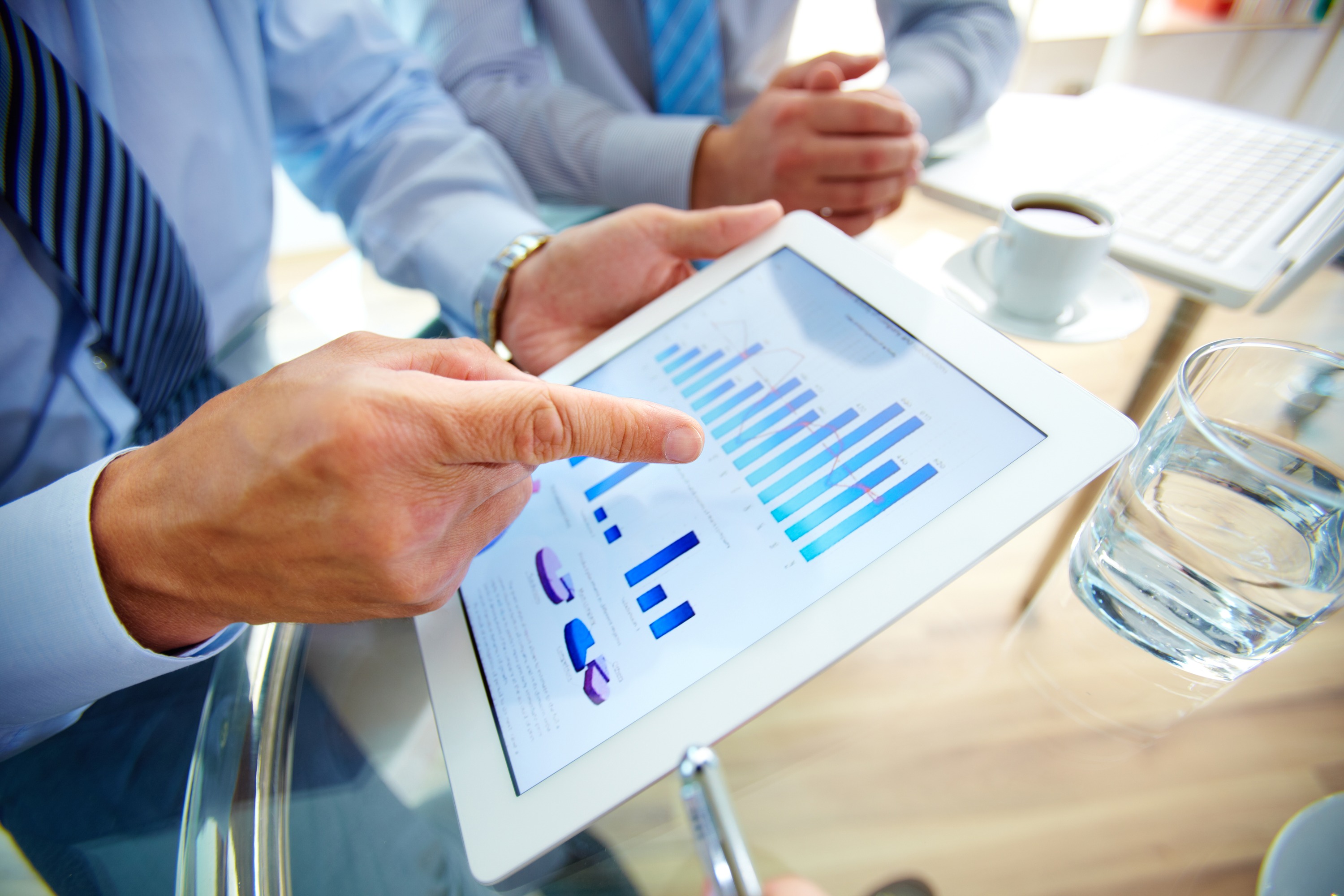 Contemporary business Modern people doing business, graphs and charts being demonstrated on the screen of a touchpad