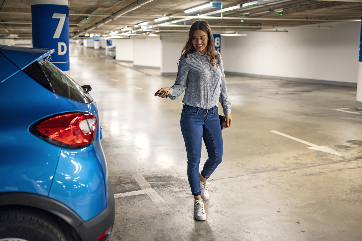 Woman in a parking, unlocking in her car. Woman activating her c